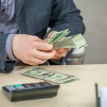 Young businessman working from his office and counting cash money