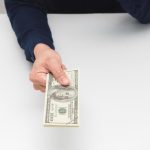 man-hand-giving-money-dollar-on-the-table-earn-salary-concept-free-photo